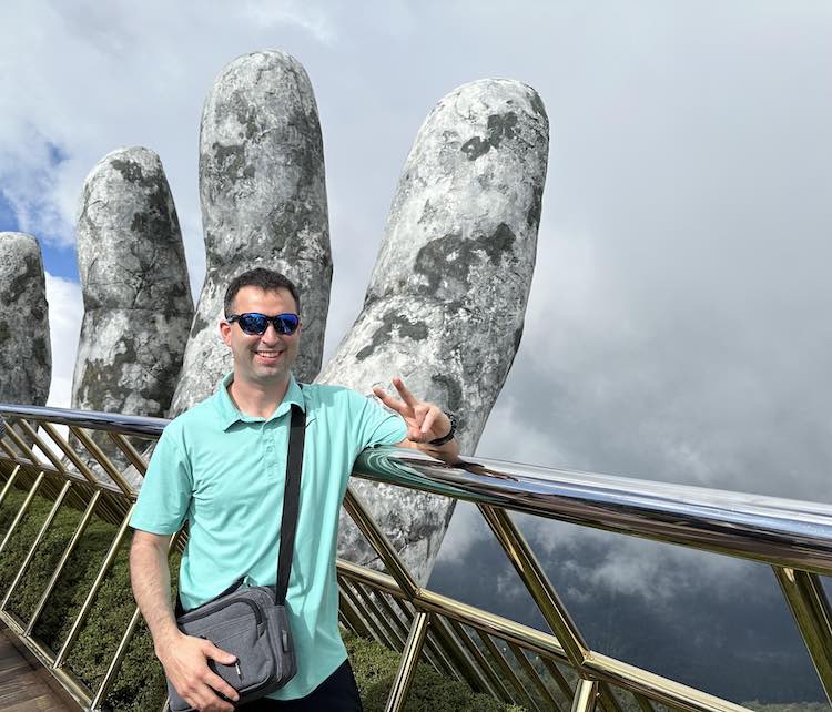 Eric James wearing an over-the-shoulder bag at Golden Hills Bridge at Ba Na Hills, Vietnam.