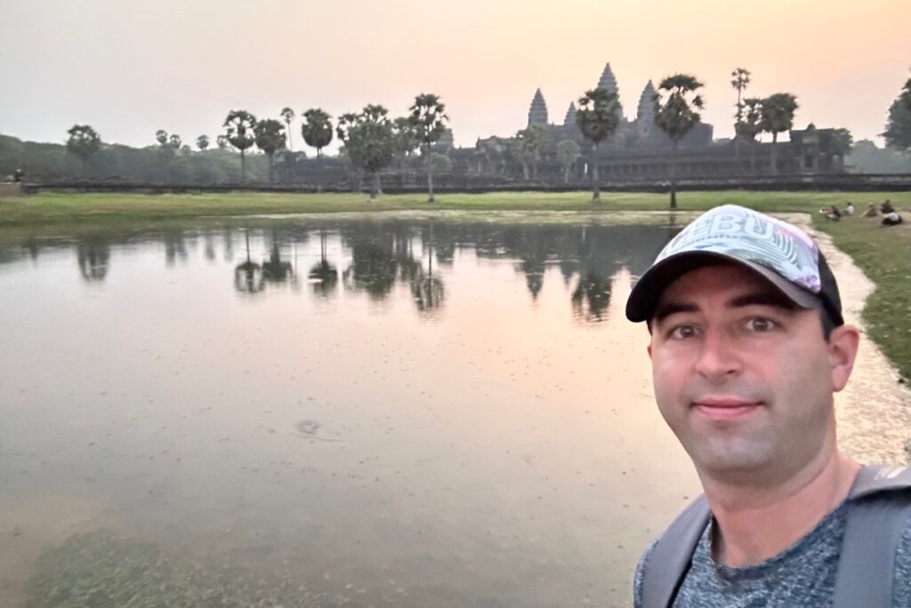 American tourist visits Angkor Wat, Siem Reap, Cambodia at dawn.