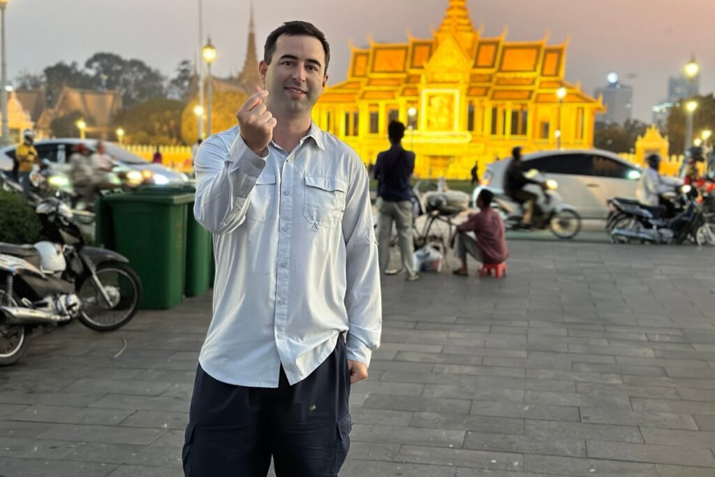 American tourist hanging out in Riverside in front of the Golden Temple in Phnom Penh, Cambodia at sunset.