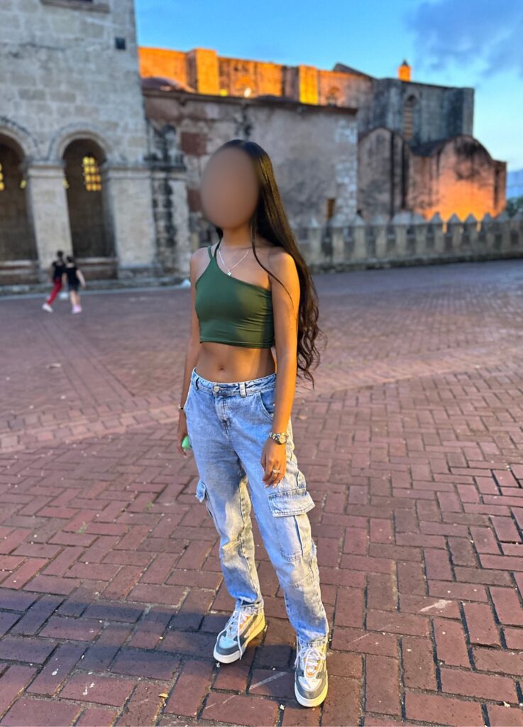 Beautiful Dominican woman standing in front of the Fortress of Columbus (Alcázar de Colón) in Zona Colonial, Santo Domingo, Dominican Republic.