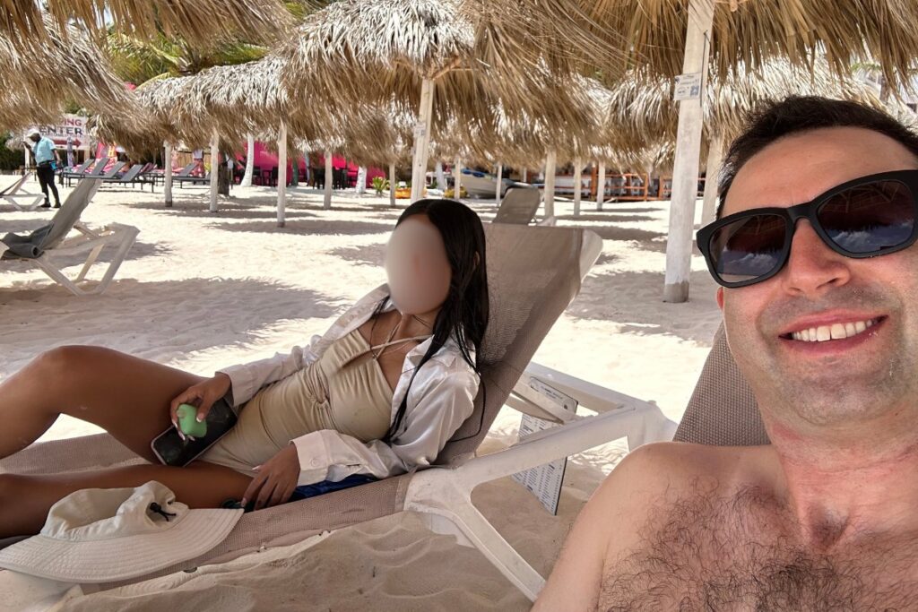 Image of beautiful Dominican woman with her American boyfriend under a tropical cabana in Bavaro Beach, Punta Cana, Dominican Republic.