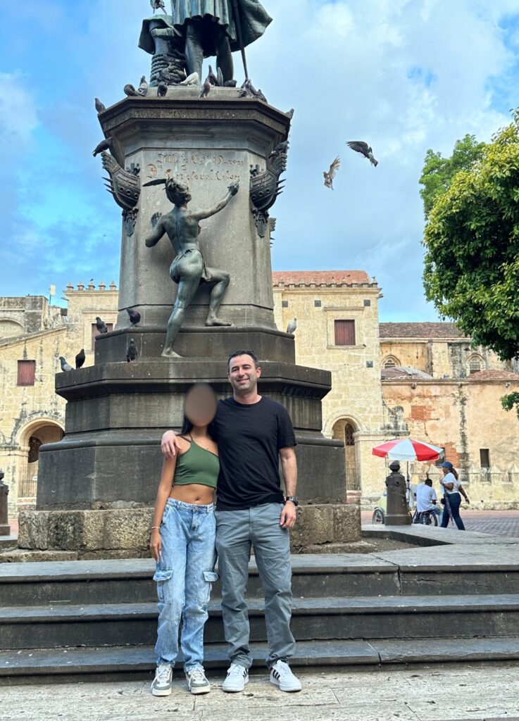 Hot Dominican woman with American boyfriend standing in front of Christopher Columbus statue in Zona Colonial, Santo Domingo, DR.