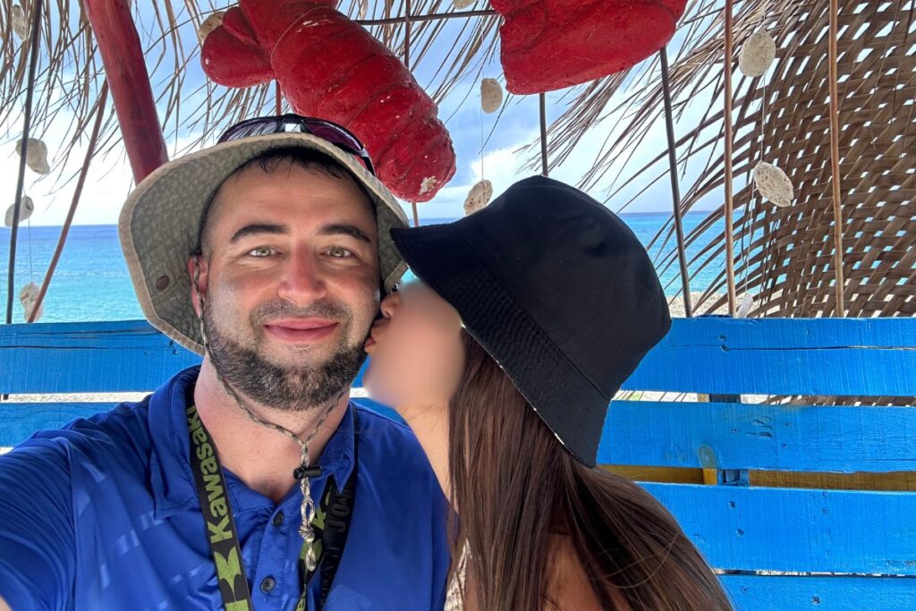 American man getting a kiss from a date with gorgeous Colombian woman in San Andres, Colombia.